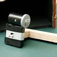 Image shows wooden arm supporting the film canister pinhole camera (no 37) attached to the side of 24hr clock. (nestbox in the background) Copyright Anthony Carr